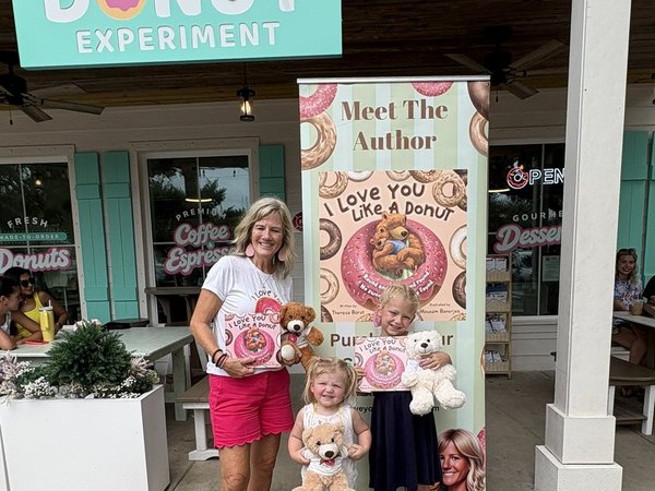 Theresa with two young readers and her author banner in front of The Donut Experiment