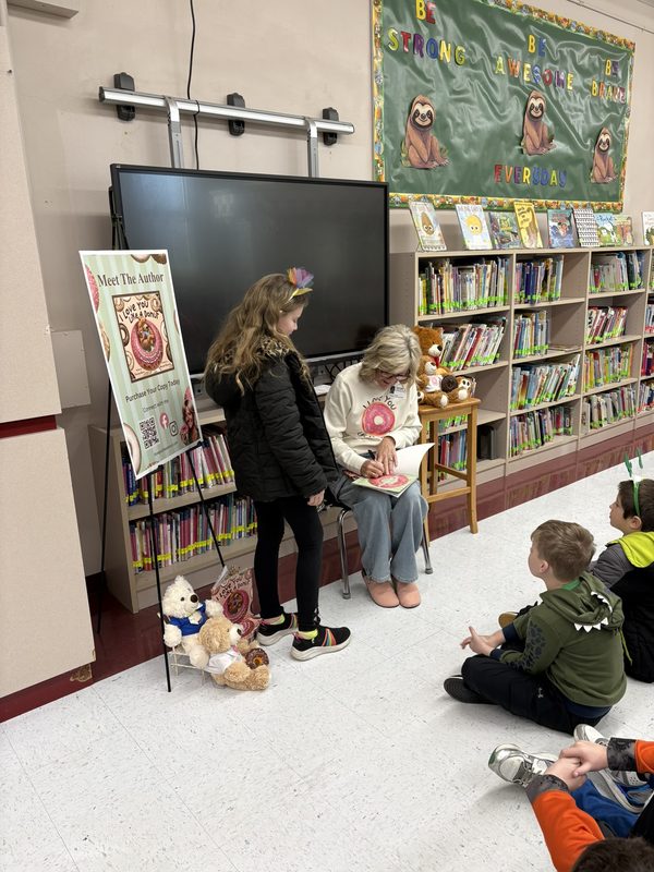 Theresa signing a book for a child in a library